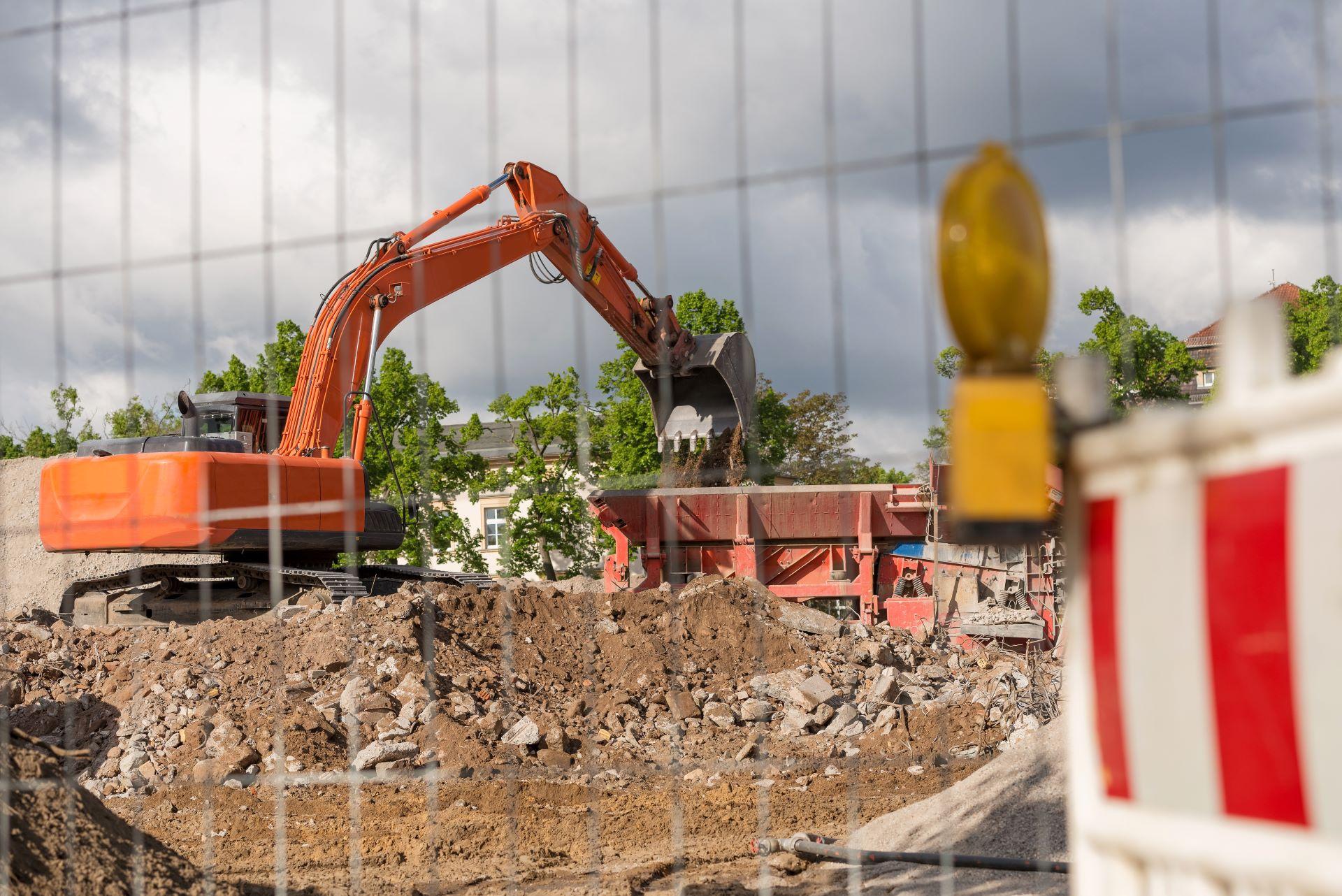 Bagger entlädt Aushub in Container auf Baustelle