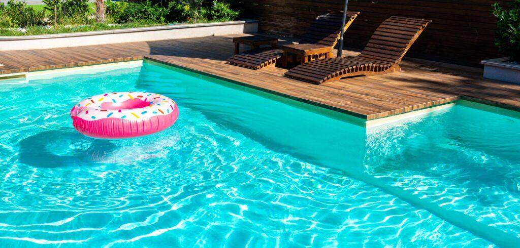 Klarer Gartenpool mit Sonnenliege im Sommer